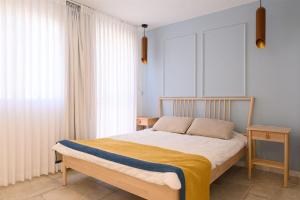 a bedroom with a bed with a yellow blanket on it at זוהר על הים - ווילה ו-3 חדרי סטודיו מהממים עם בריכה בנווה זוהר in Neve Zohar