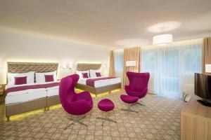 a hotel room with a bed and two purple chairs at Pytloun Wellness Hotel Harrachov in Harrachov