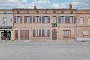 an old brick building on the side of a street at La Demeure De Jeanne in Cadours