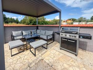 d'une terrasse avec un grill, une table et des chaises. dans l'établissement Villa Lara II with private pool, à Ližnjan