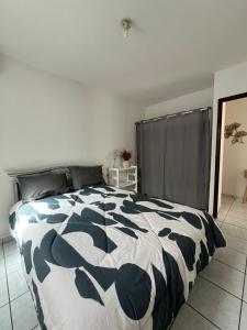 a bedroom with a bed with a black and white comforter at Azalée in Saint-Paul