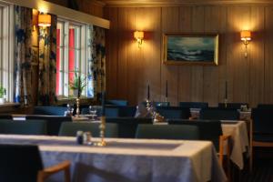 a dining room with tables and chairs and a painting on the wall at Smedsgården Hotel in Nesbyen