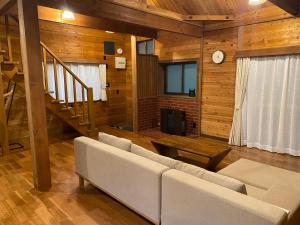 a living room with a white couch and a staircase at Komore Villa Kita-Karuizawa こもれヴィラ北軽井沢 in Tsumagoi
