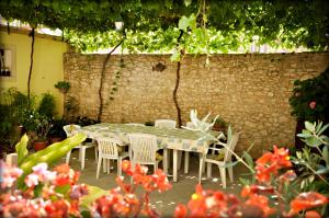 a table and chairs in a garden with a stone wall at Apartments Lumbarda in Lumbarda