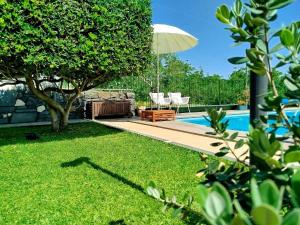 a backyard with a pool with a table and an umbrella at Villa Capogrecale - piscina riscaldata in Piedimonte Etneo