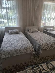 2 camas en una habitación con ventanas y cortinas en IVA guest House, en Karakol 5 fotos más