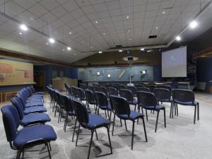 a conference room with blue chairs and a screen at Hotel Las Torres Patagonia in Torres del Paine