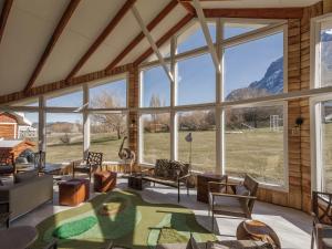 a living room with large windows and a view of a field at Hotel Las Torres Patagonia in Torres del Paine