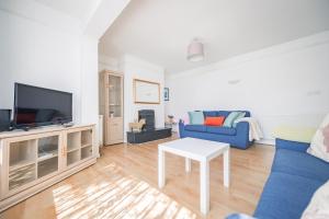 a living room with a blue couch and a tv at Charming Family-Friendly 3-Bedroom House with Parking & Spacious Garden in Milton