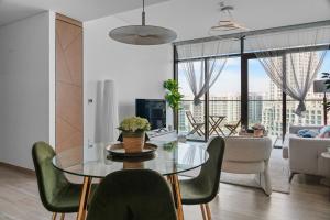 a dining room with a glass table and green chairs at Palace Residence Chic 2BR Creek Beach View in Dubai