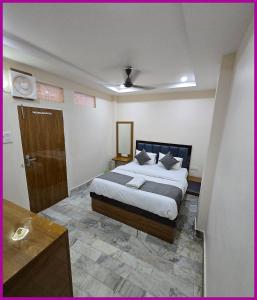 a bedroom with a king sized bed and a wooden door at V - PREMIUM R - GH - Varanasi - Free Wi-Fi & Parking - Near The Holy Kashi Vishwanath Temple! in Varanasi