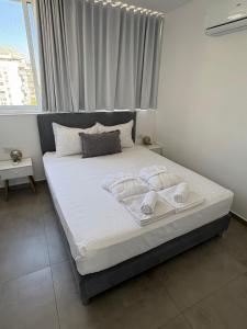 a bedroom with a bed with white sheets and pillows at Boutique apartment in Rishon LeẔiyyon