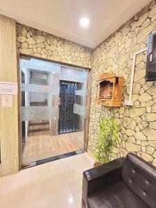 a living room with a stone wall and a couch at S R Hotel in Surat +7 photos