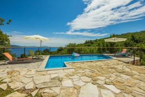 a swimming pool with a view of the water at Ivanini secluded stone Villa with a stunning view in Brseč