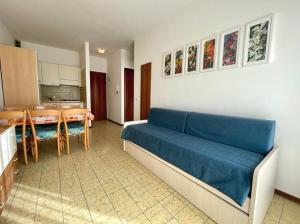 a living room with a blue couch and a kitchen at Flat with balcony 370mt from the sea in Caorle