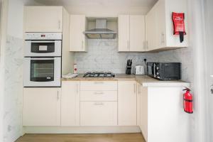 a white kitchen with white cabinets and appliances at Charming Family-Friendly 3-Bedroom House with Parking & Spacious Garden in Milton