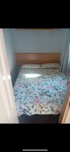a small bedroom with a bed with a floral comforter at Seawick Staycay in Saint Osyth +2 photos
