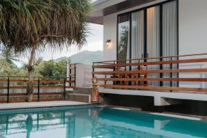 a house with a swimming pool and a balcony at Yoki's Bungalows in Kuta Lombok