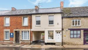 an old brick house with a white door on a street at Newly renovated 2-bed house in Lechlade with parking in Lechlade