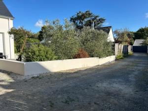 a white retaining wall with bushes on a street at La gildasienne in Saint-Gildas-de-Rhuys