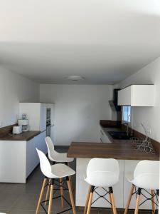 a kitchen with white chairs and a wooden counter at La gildasienne in Saint-Gildas-de-Rhuys