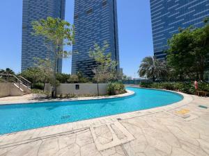 a swimming pool in the middle of two tall buildings at Urban Oasis 1BR Apartment in Gate Towers in Abu Dhabi