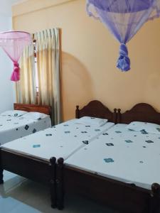 阿努拉德普勒Ranmini Family Resort的房间里有两张床，装饰有蓝色和紫色