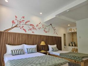a bedroom with two beds and a tree mural on the wall at Kyle's Bed and Breakfast DMall Boracay in Boracay