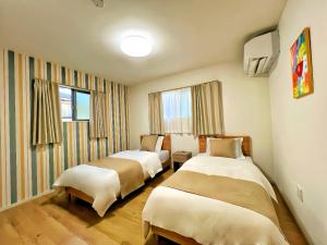 a room with two beds and a tv and windows at 藍遊び in Fukuoka
