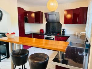 une cuisine avec des placards rouges et une table en bois dans l'établissement Gîte normand climatisé avec piscine privée, à Condé-sur-Seulles