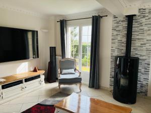 un salon avec une télévision à écran plat et une chaise dans l'établissement Gîte normand climatisé avec piscine privée, à Condé-sur-Seulles