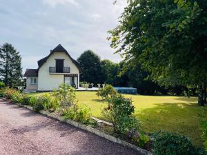une petite maison blanche avec une cour gazonnée dans l'établissement Gîte normand climatisé avec piscine privée, à Condé-sur-Seulles