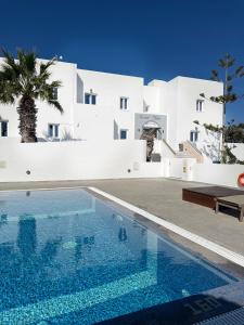 a swimming pool in front of a white building at Nikos Hotel in Karterados