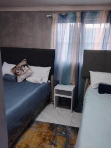 Un dormitorio con dos camas y una mesa y una ventana. en Vumasky 2, en Ladysmith