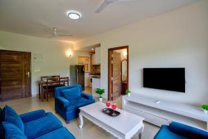 a living room with a blue couch and a tv at Lush View 2BHK Apartments in Candolim in Candolim