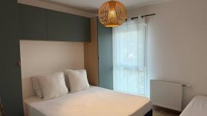 Un dormitorio con una cama con sábanas blancas y una ventana. en "Lac'Almie" - Appartement 2 chambres avec Terrasse et Parking, en Doussard