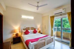 a bedroom with a white bed with red pillows and a window at Lush View 2BHK Apartments in Candolim in Candolim