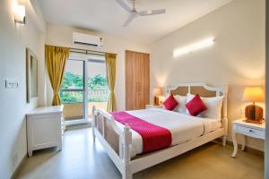 a bedroom with a white bed and a window at Lush View 2BHK Apartments in Candolim in Candolim +22 photos