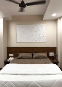 a bedroom with a large white bed with a ceiling at Krushnkunj Executive in Kolhapur