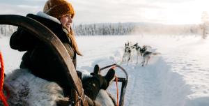 a woman is pulling a group of dogs on a sled at Lapland Hotels Pallas in Pallastunturi