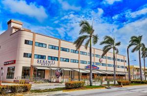 a large white building with palm trees in front of it at Serenti Hotel Saipan in Garapan