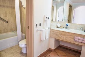 a bathroom with a sink and a toilet and a mirror at Sandos Finisterra All Inclusive in Cabo San Lucas