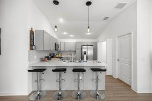 a kitchen with white cabinets and bar stools at Cozy 2BR With Golfcart 5 Mins to Eastport Sq in Wildwood