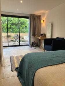 a bedroom with a bed and a view of a patio at Studio neuf dans un écrin de verdure in Charbonnières-les-Bains