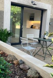 a patio with a table and chairs in front of a door at Studio neuf dans un écrin de verdure in Charbonnières-les-Bains