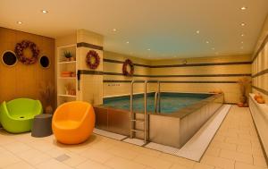 a bathroom with a swimming pool with an orange chair at Mercure Hotel Duisburg City in Duisburg