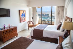 a hotel room with two beds and a television at Sandos Finisterra All Inclusive in Cabo San Lucas