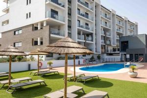 eine Wohnung mit Pool und Liegen und Sonnenschirmen in der Unterkunft Luxury apartment - Sea, Mountain, Golf - La Duquesa Manilva in Manilva