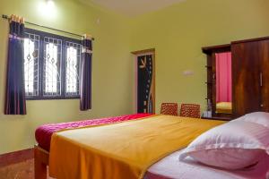 a bedroom with a large bed with yellow walls and windows at Lakeside Room stay in Yelagiri