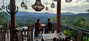 two people sitting at tables on the balcony of a restaurant at Shining Green View in Ella